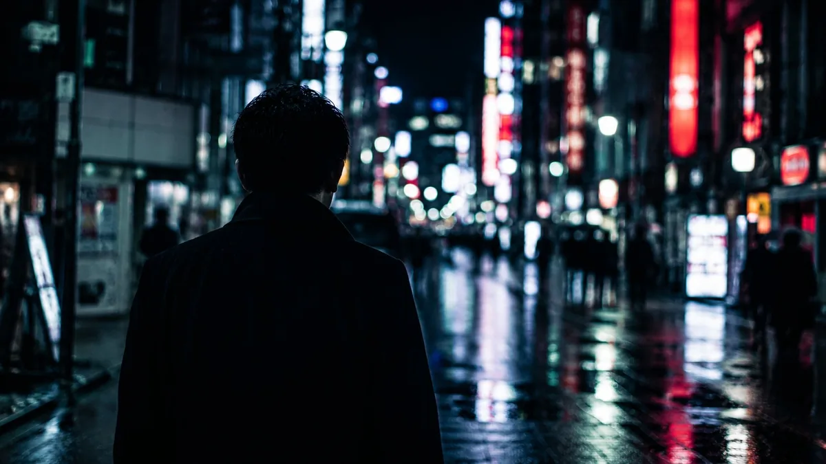 夜の繁華街を一人で歩き相手を探す男性のイメージ