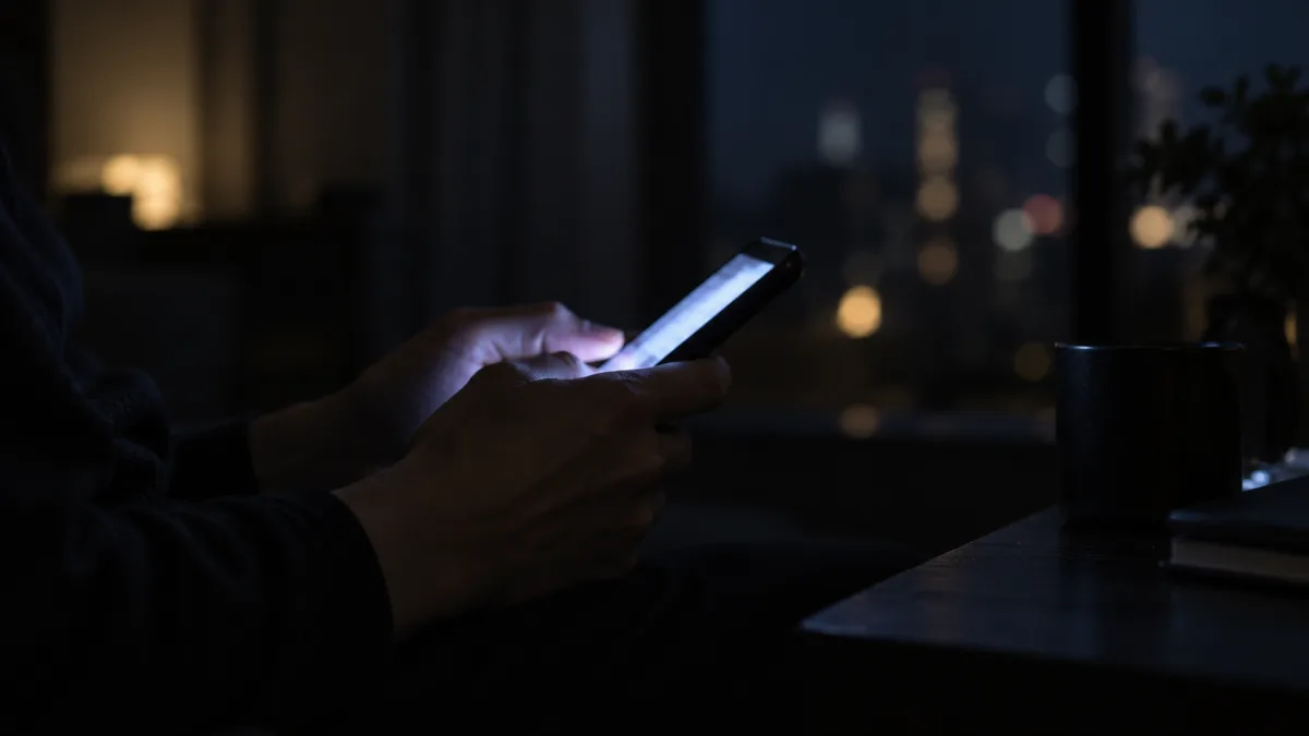 暗い部屋でスマートフォンの画面に照らされた手元