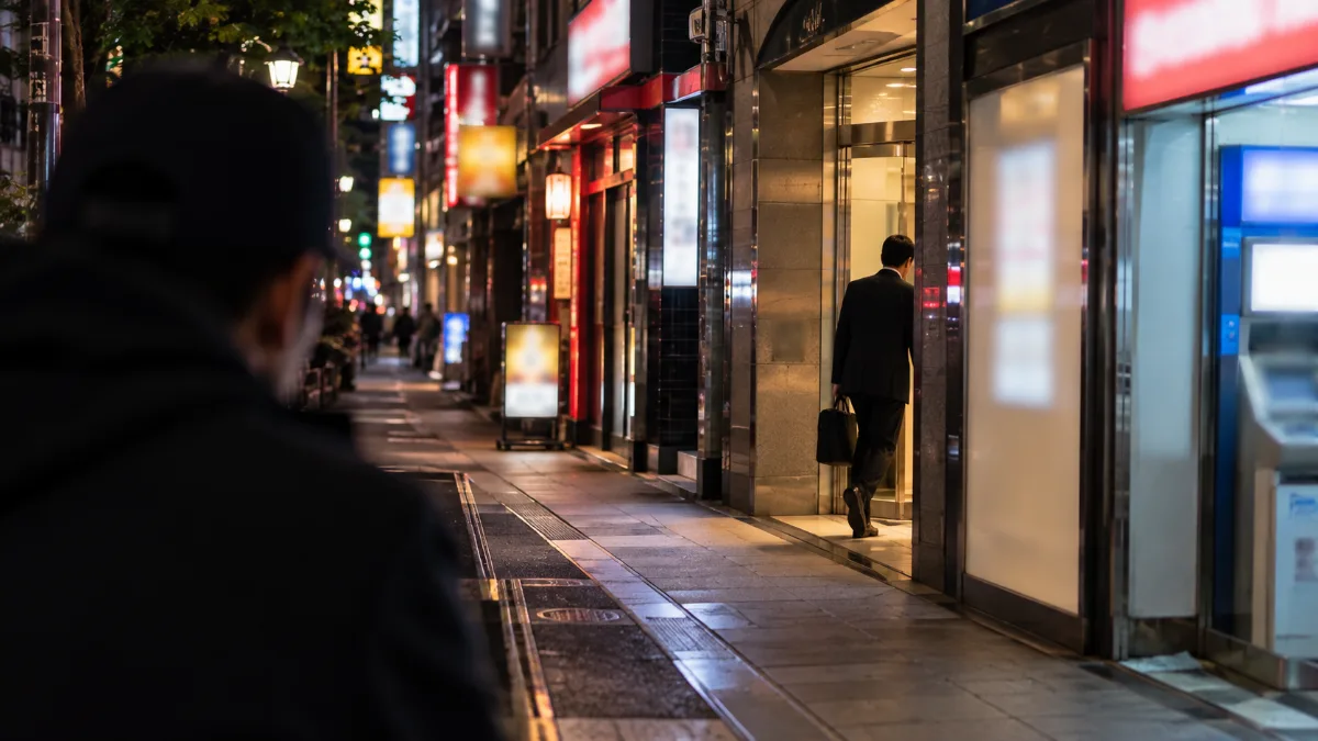 夜の新宿の雑居ビル街を離れた位置から確かめる調査員の視点